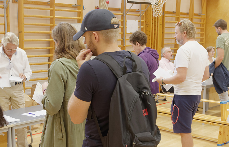 Fyra personer står framför en bord och en man som tar emot papper